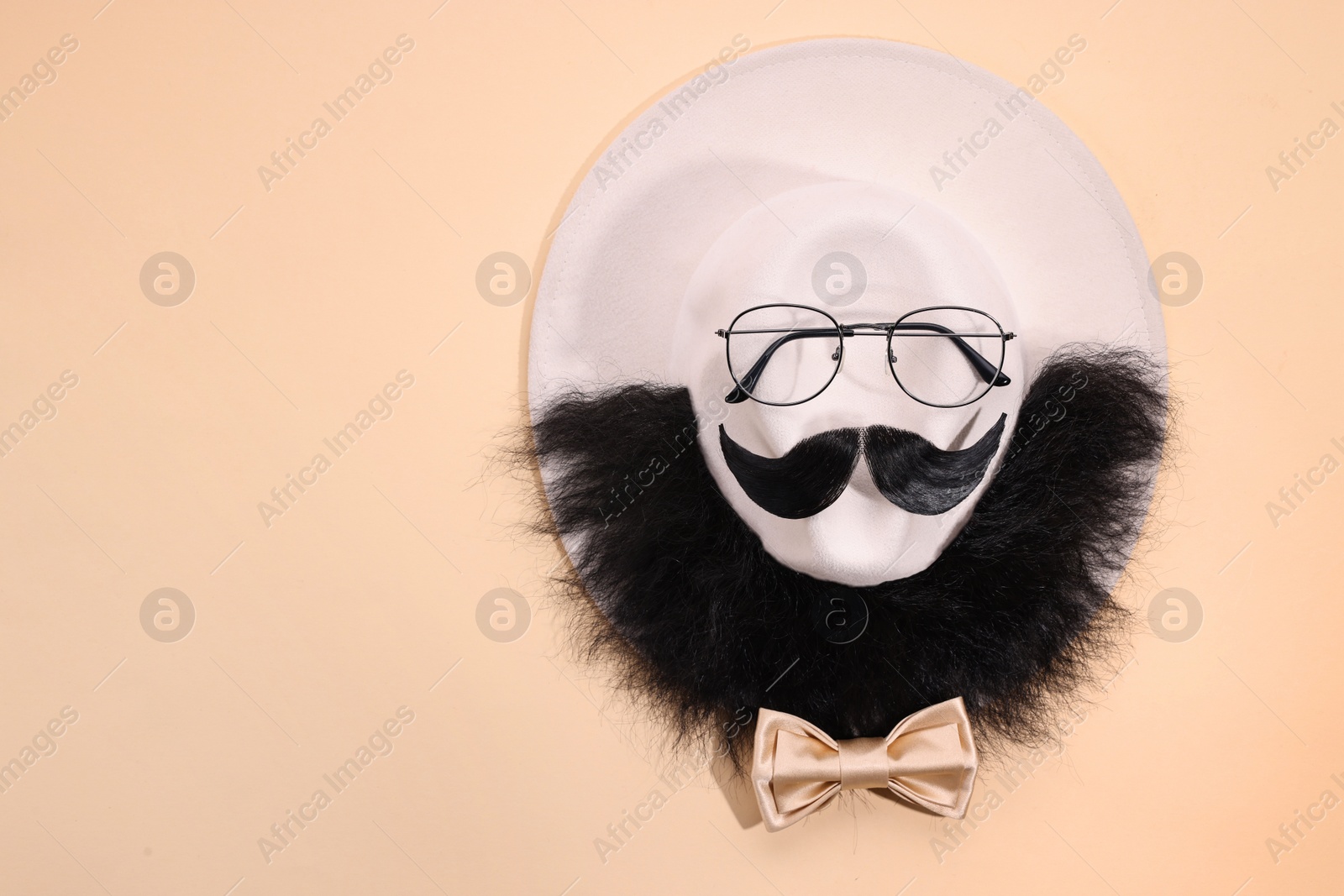 Photo of Man's face made of artificial mustache, beard and glasses on beige background, top view. Space for text
