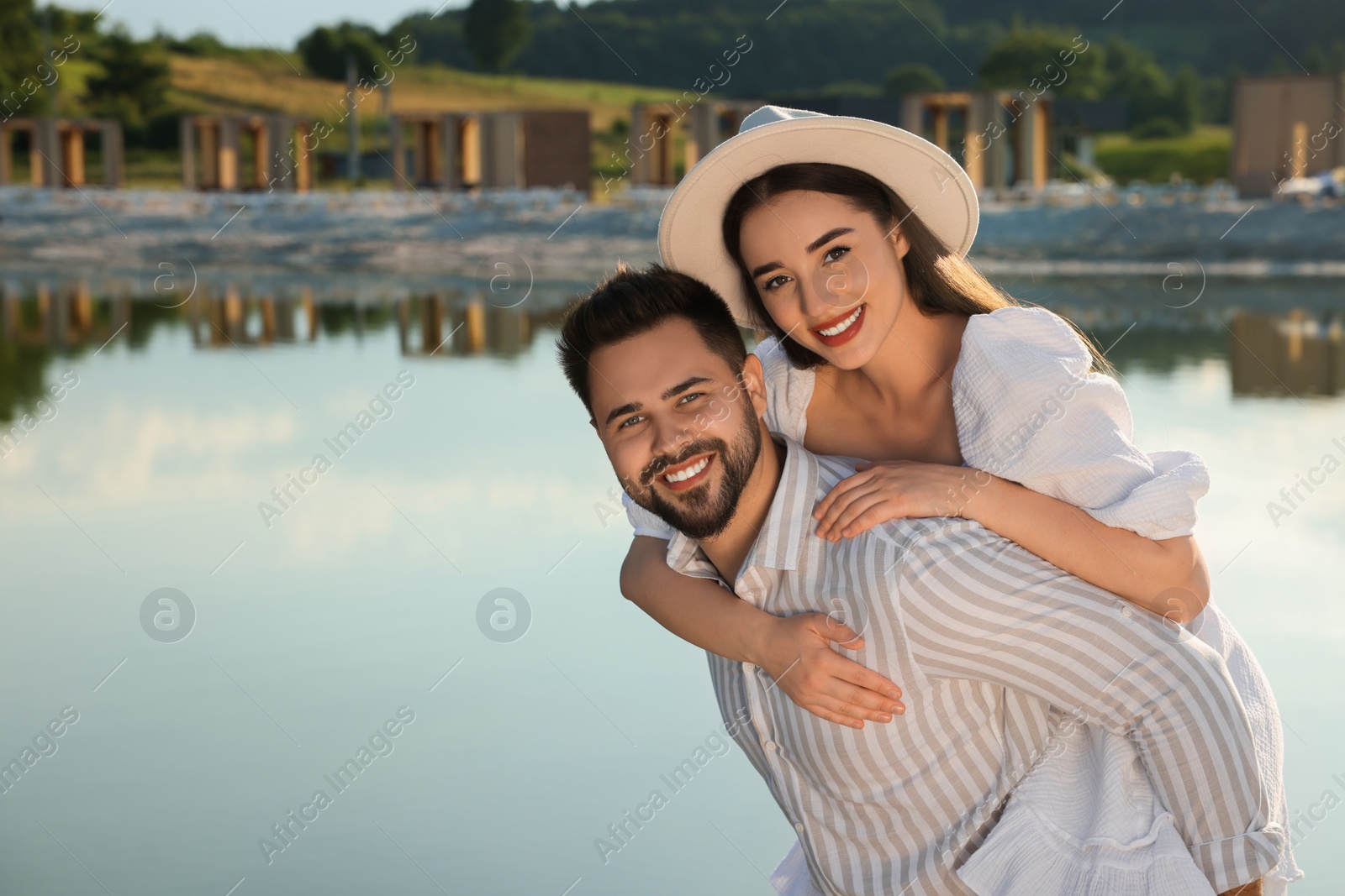 Photo of Romantic date. Beautiful couple spending time together near lake, space for text