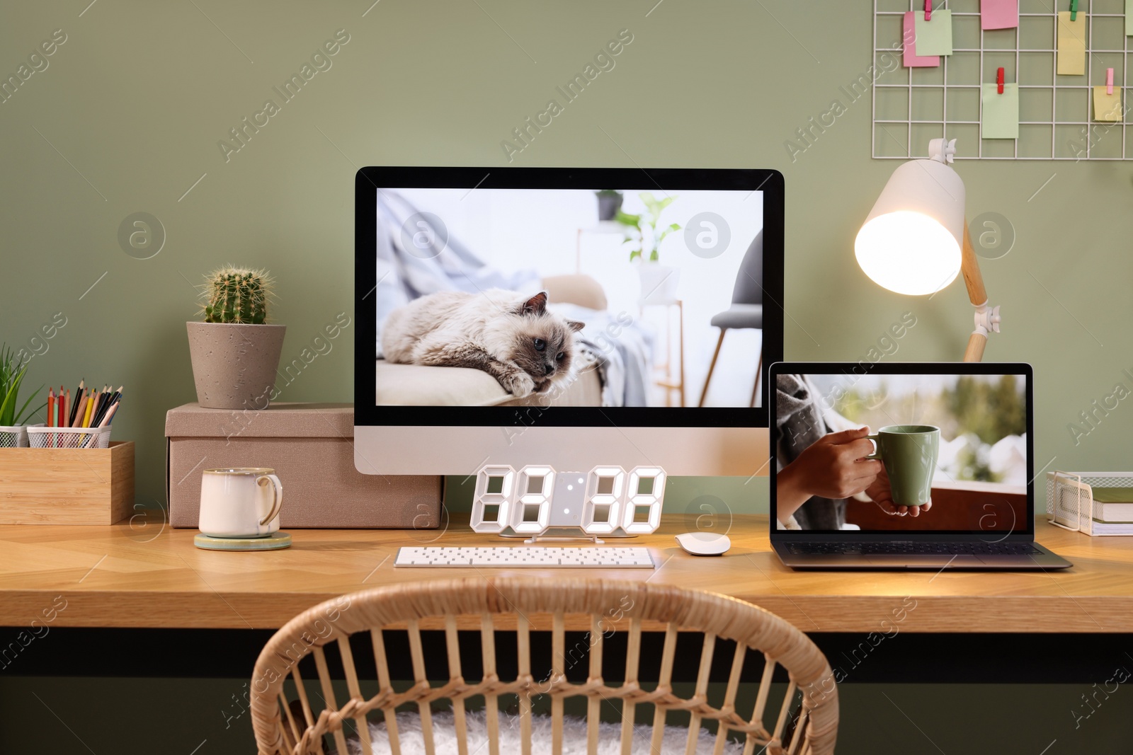 Photo of Stylish workplace with computer, laptop and lamp near olive wall at home