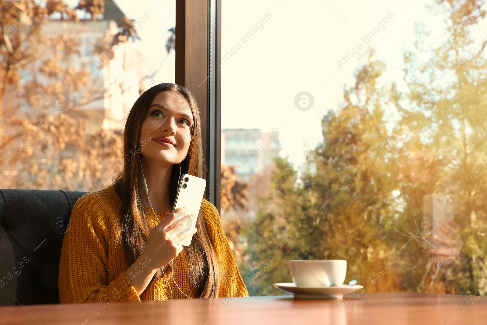 Photo of Woman listening to audiobook at table in cafe