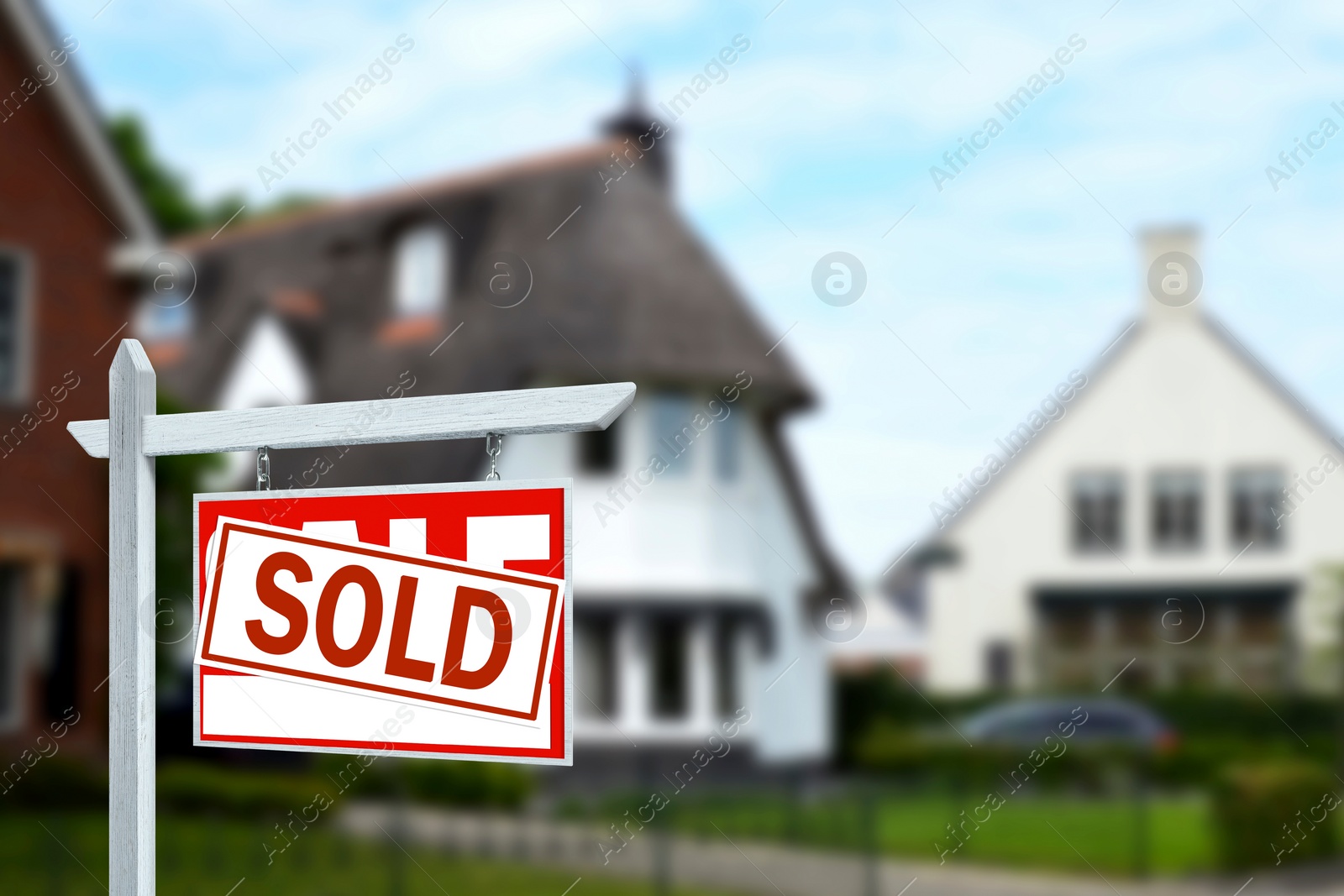 Image of Red sale sign with Sold sticker near house