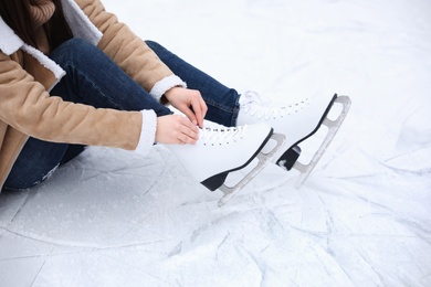 Photo of Woman lacing figure skate while sitting on ice, closeup