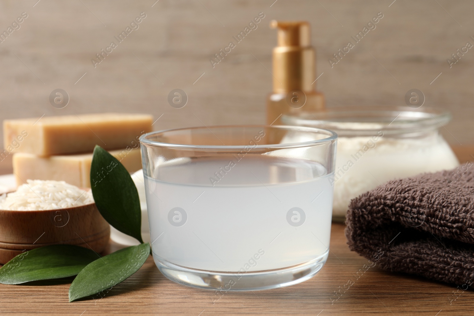 Photo of Homemade natural rice water and cosmetic products on wooden table