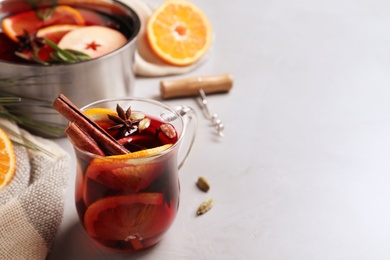 Photo of Glass cup of tasty mulled wine on grey table. Space for text