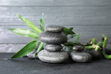 Photo of Stacked zen stones and bamboo leaves on table against wooden background