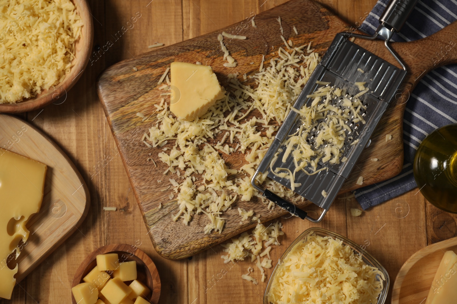 Photo of Different types of cheese and grater on wooden table, flat lay