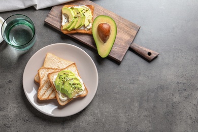 Photo of Flat lay composition with toasted bread and avocado on grey background