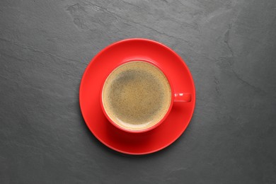 Photo of Aromatic coffee in red cup on black background, top view