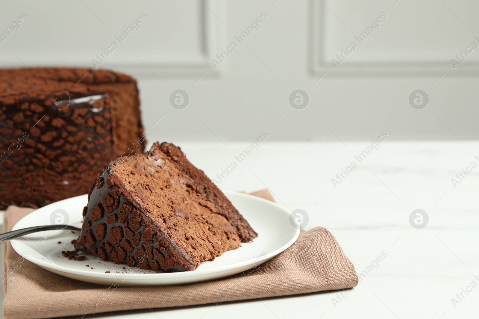 Photo of Piece of delicious chocolate truffle cake on white table, space for text
