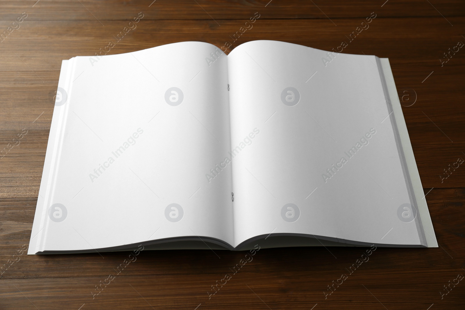 Photo of Open blank paper brochure on wooden table. Mockup for design