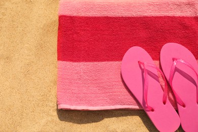 Photo of Beach towel with slippers on sand, top view. Space for text