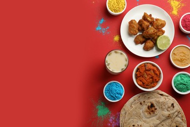 Flat lay of traditional Indian food and color powder dyes on red background, space for text. Holi festival