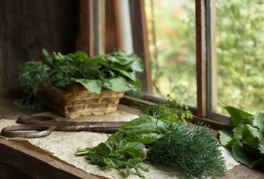 Photo of Different herbs and rusty scissors on wooden windowsill indoors, space for text