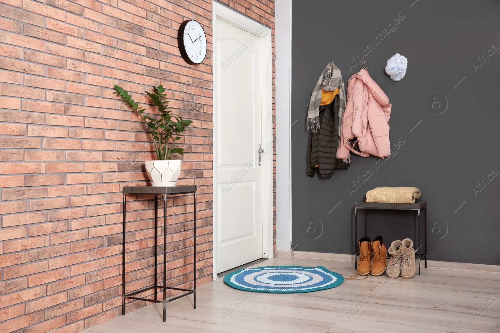 Photo of Modern hallway interior with stylish furniture and clothes on wall