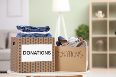 Photo of Donation boxes with clothes and shoes on table indoors