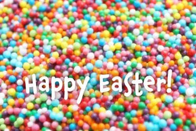 Image of Text Happy Easter and bright colorful sprinkles as background, closeup. Confectionery decor