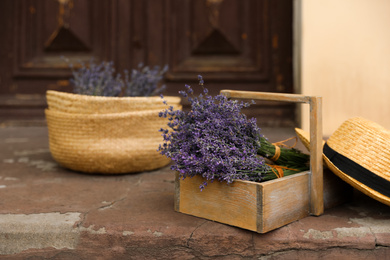 Wooden basket with lavender flowers and straw hat near building outdoors