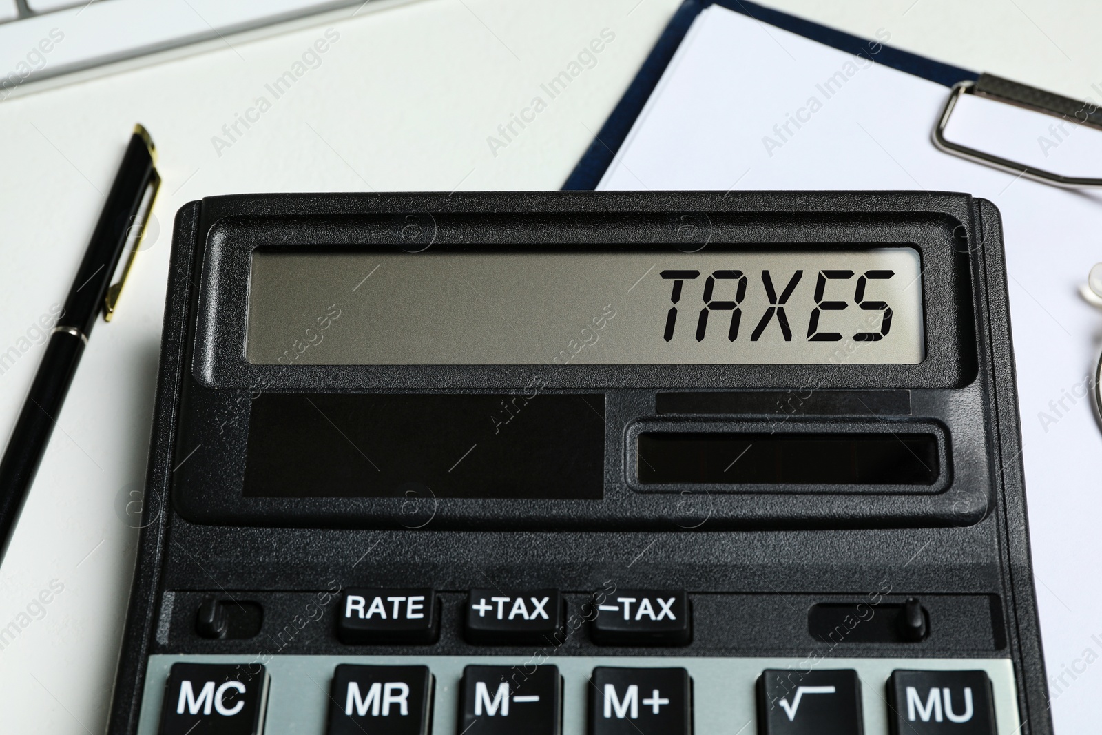 Image of Calculator with word Taxes, documents and pen on table, closeup