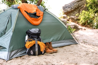 Camping tent with sleeping bag, boots and backpack on beach