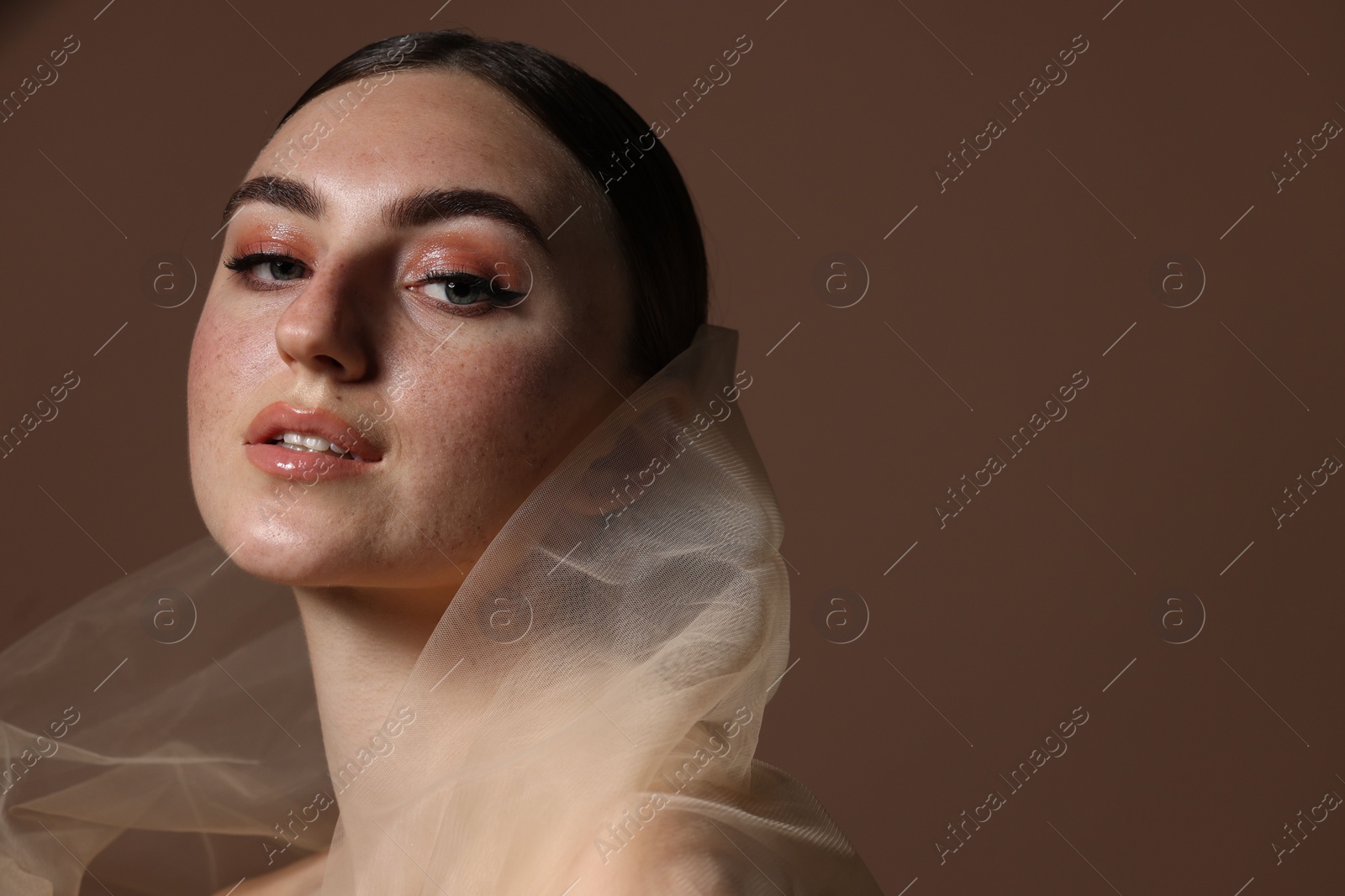 Photo of Fashionable portrait of beautiful woman with fake freckles on brown background. Space for text