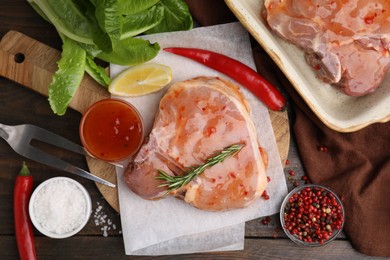 Photo of Flat lay composition with raw marinated meat, lemon, rosemary and spices on wooden table