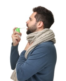 Photo of Young man with scarf using throat spray on white background