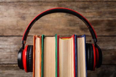 Books and modern headphones on wooden background, closeup