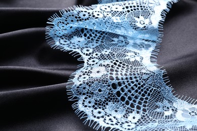 Photo of Beautiful light blue lace on black fabric, closeup