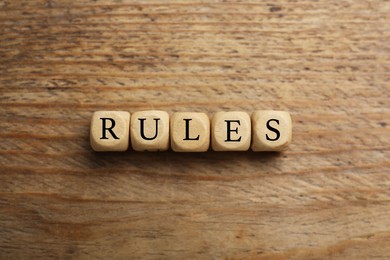 Photo of Word Rules made of cubes with letters on wooden table, top view