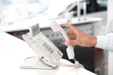 Salesman answering call at desk in car salon