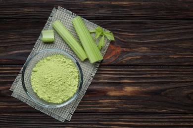 Natural celery powder in bowl and fresh stalks on wooden table, top view. Space for text