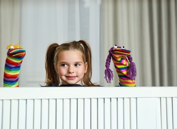 Cute little girl performing puppet show at home