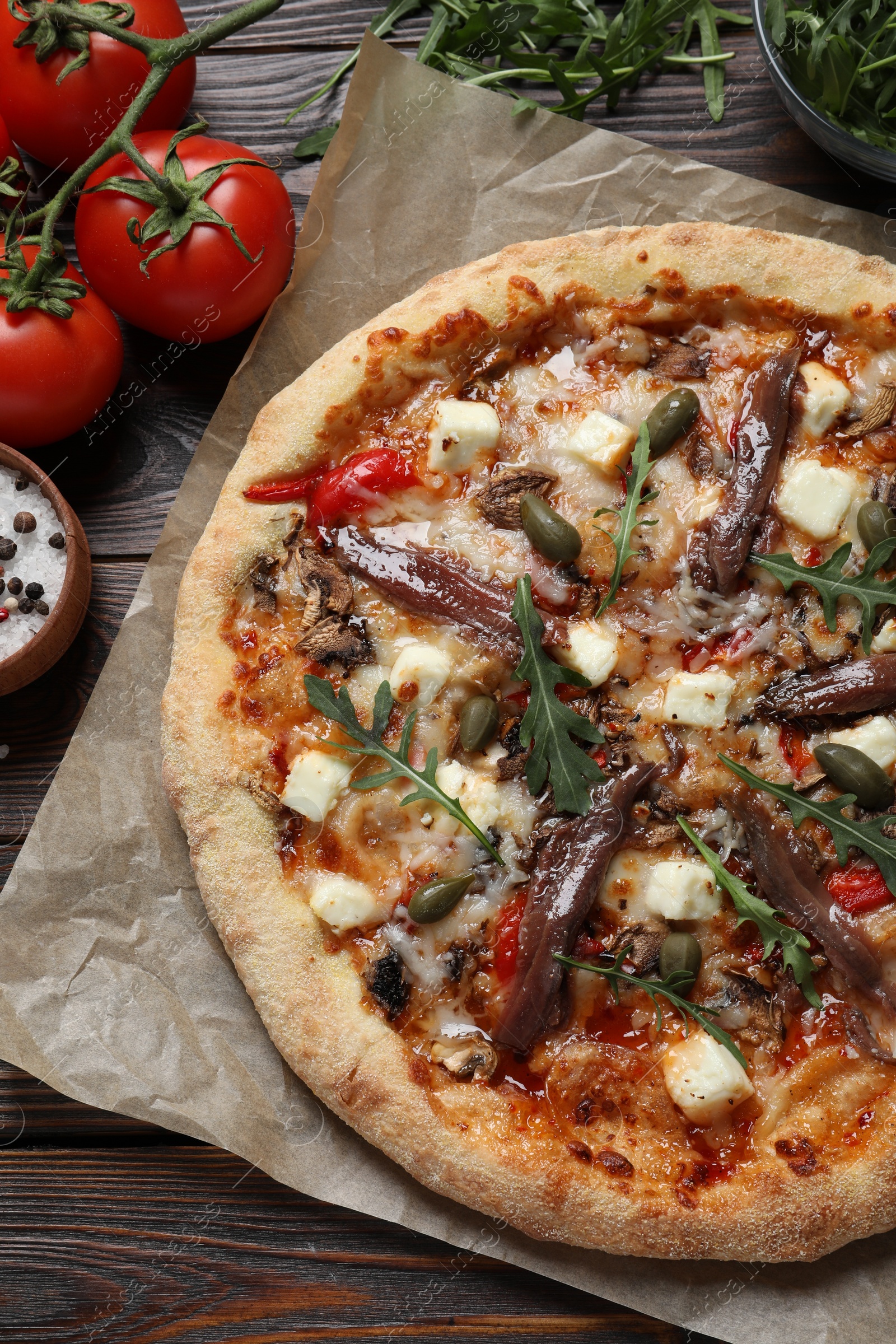 Photo of Tasty pizza with anchovies and ingredients on wooden table, flat lay