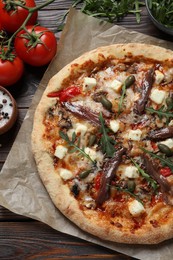 Photo of Tasty pizza with anchovies and ingredients on wooden table, flat lay