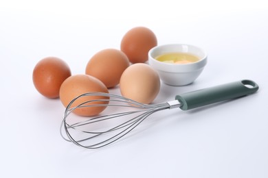 Photo of Whisk, whole and broken eggs isolated on white