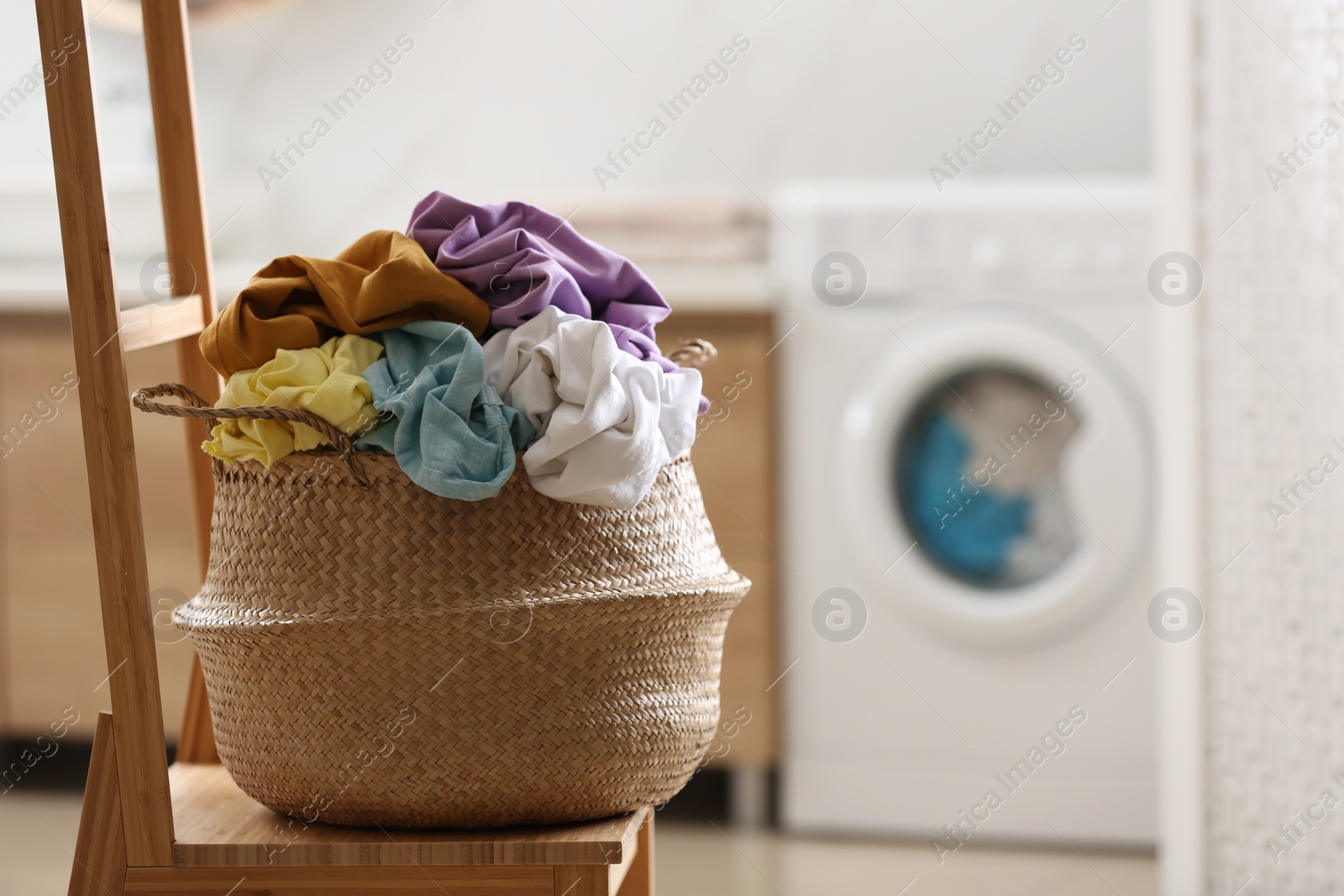 Photo of Wicker basket with dirty clothes on chair in bathroom. Space for text