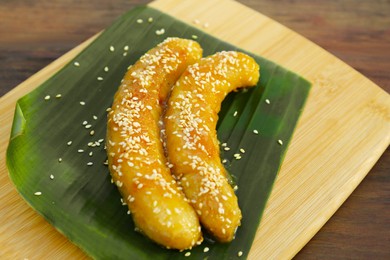 Photo of Board with delicious fried bananas on wooden table, closeup