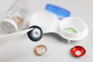 Photo of Tweezers with blue contact lens over table, closeup. Space for text
