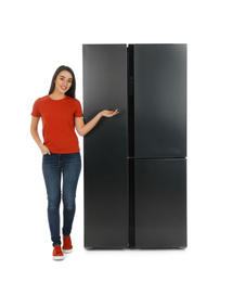 Photo of Young woman near refrigerator on white background