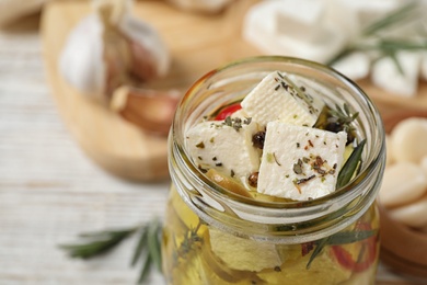 Pickled feta cheese in jar on white wooden table, closeup