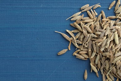 Pile of caraway seeds on blue wooden table, top view. Space for text