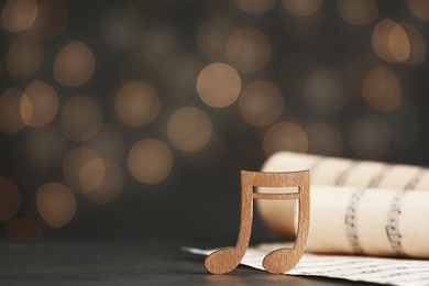 Music note and sheets on table against blurred lights, space for text. Bokeh effect