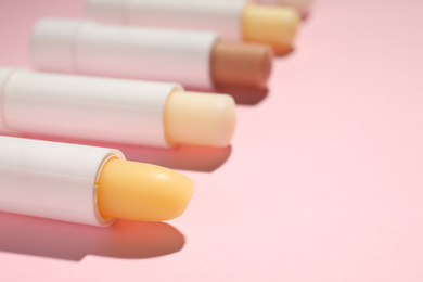 Photo of Hygienic lipsticks on pink background, closeup view