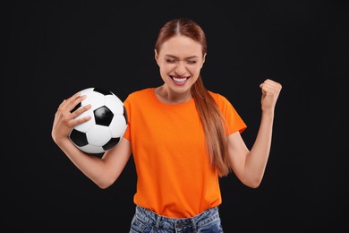 Happy fan with football ball on black background