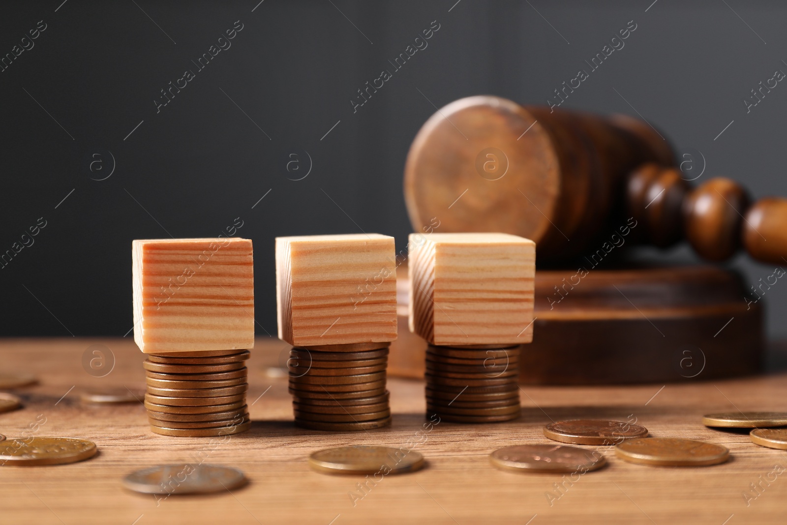 Photo of Tax law. Blank wooden cubes, coins and gavel on table, closeup