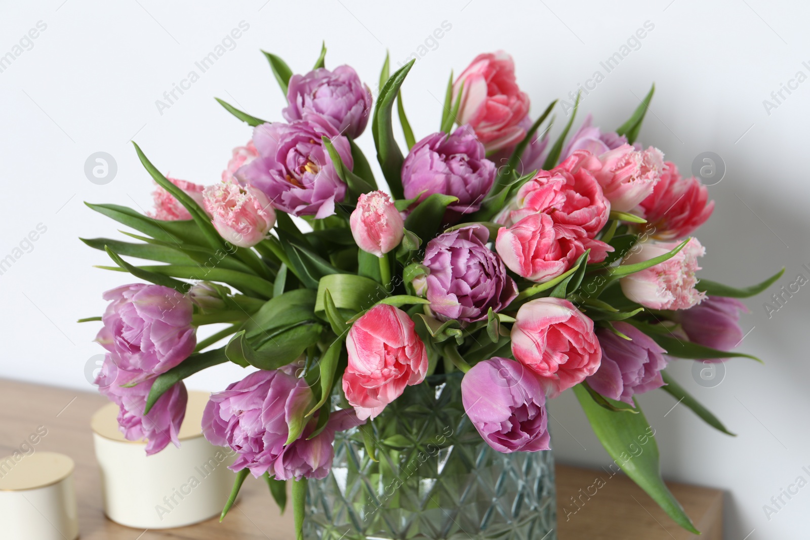 Photo of Beautiful bouquet of colorful tulip flowers near white wall, closeup