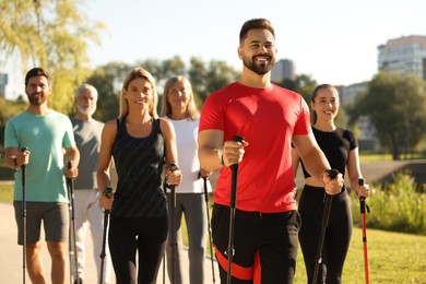 Photo of Group of happy people practicing Nordic walking with poles in park