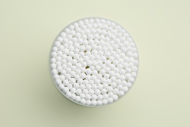 Photo of Many cotton buds in container on beige background, top view