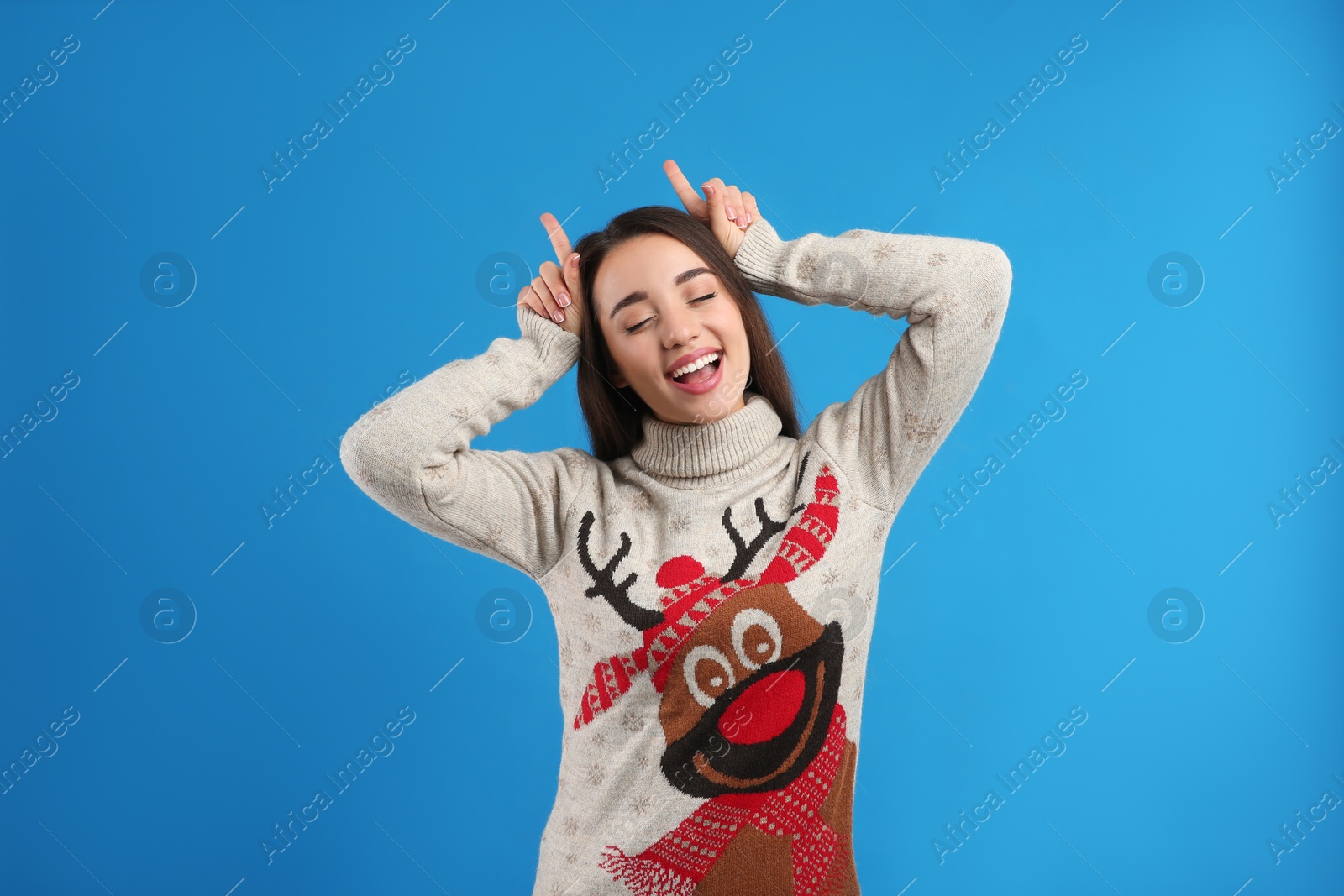Photo of Young woman in Christmas sweater on blue background