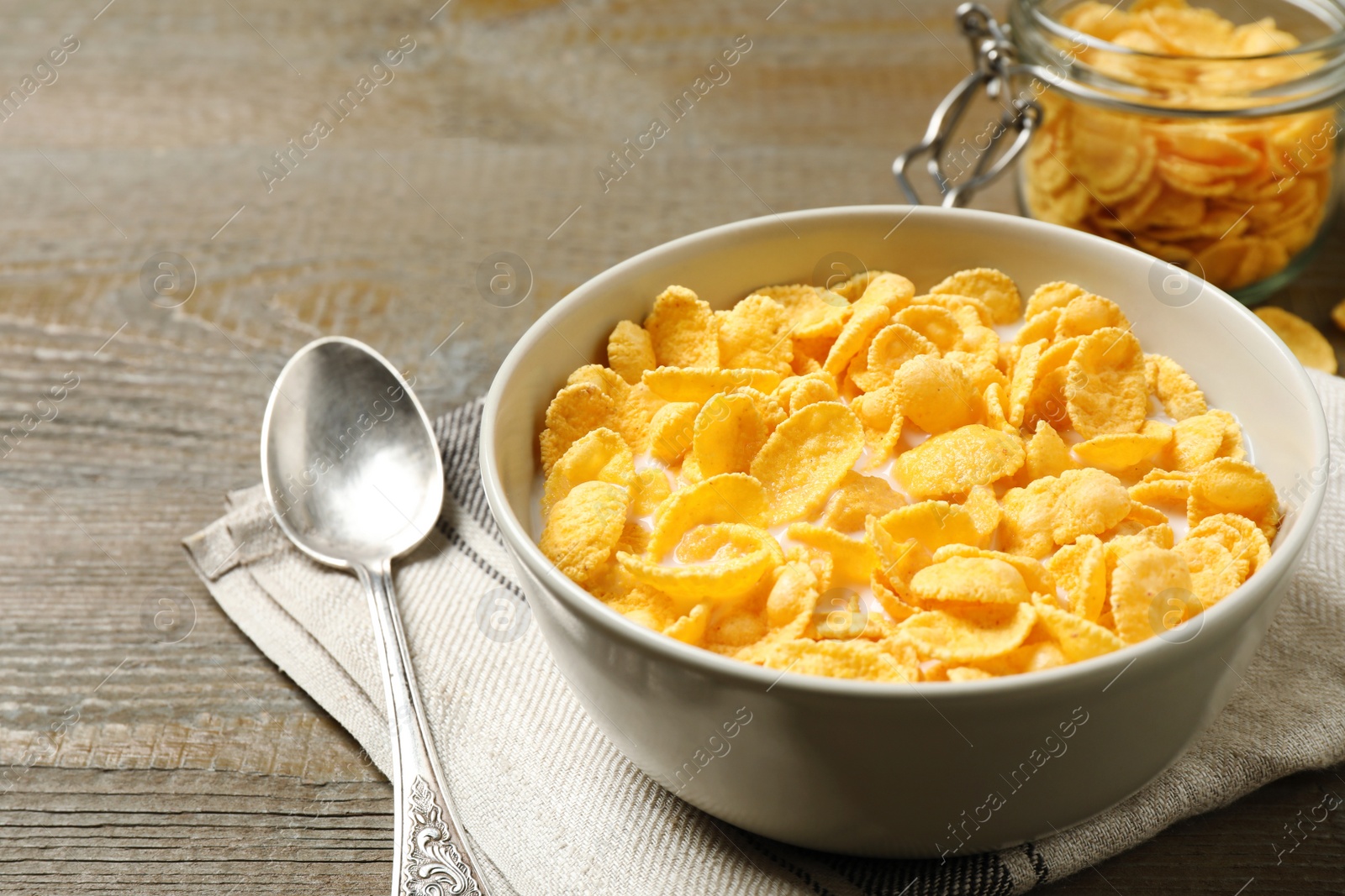 Photo of Tasty crispy corn flakes with milk on wooden  table